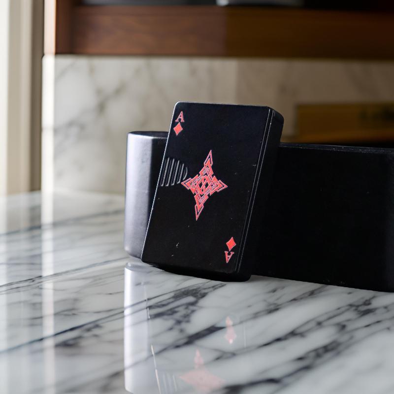 Side angle of the Ace Diamond lighter, highlighting its slim black build and stylish red diamond detail on a modern countertop.