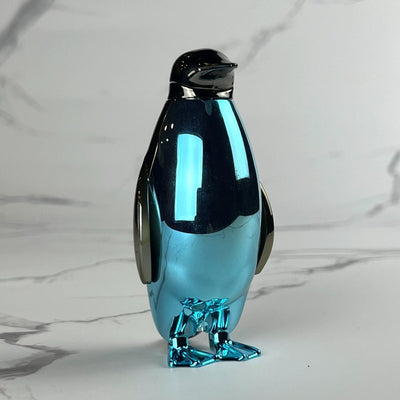 Sleek metallic blue penguin-shaped lighter with chrome wings and beak, standing upright on a marble backdrop.