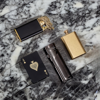 Complete Best Sellers Bundle featuring dragon, deck of cards, flamethrower, and vintage gold lighters on a luxurious marble surface.