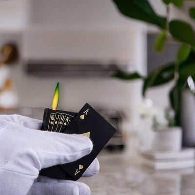 Deck of cards-style lighter with green flame, photographed in a modern kitchen setting, showcasing its unique design.