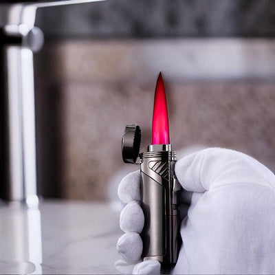 Flamethrower-style pink saber lighter with a striking red flame, held by a gloved hand against a sleek background.