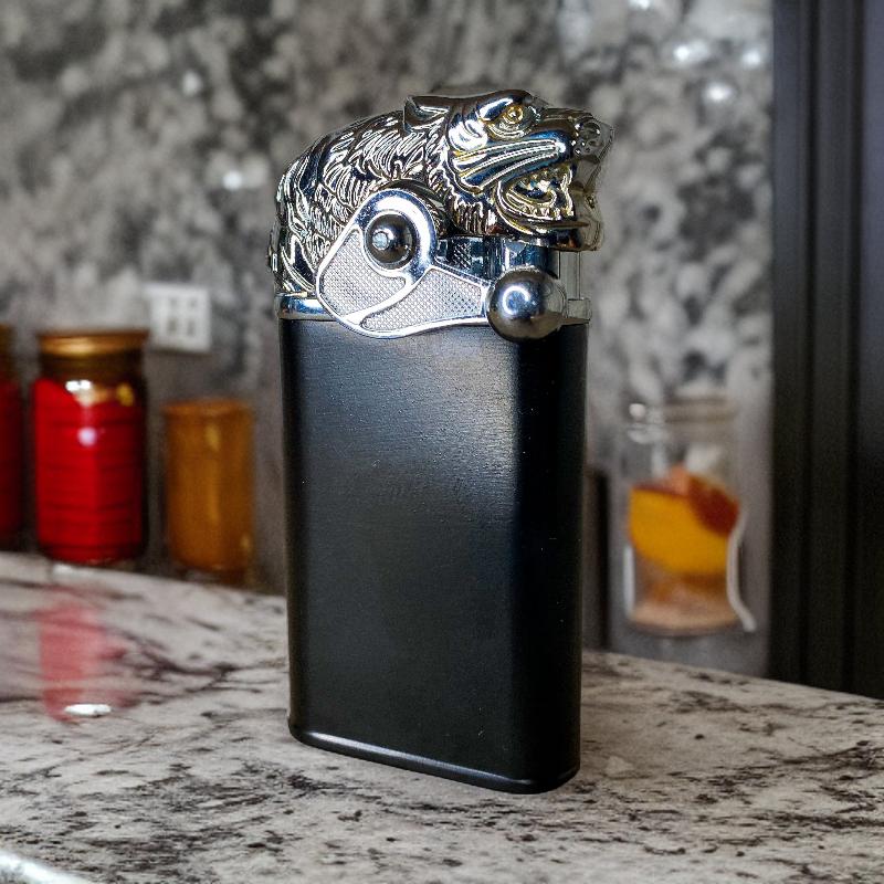 A close-up of the Big Cat Lighter featuring a detailed silver big cat head design on a sleek black body, placed elegantly on a marble countertop.