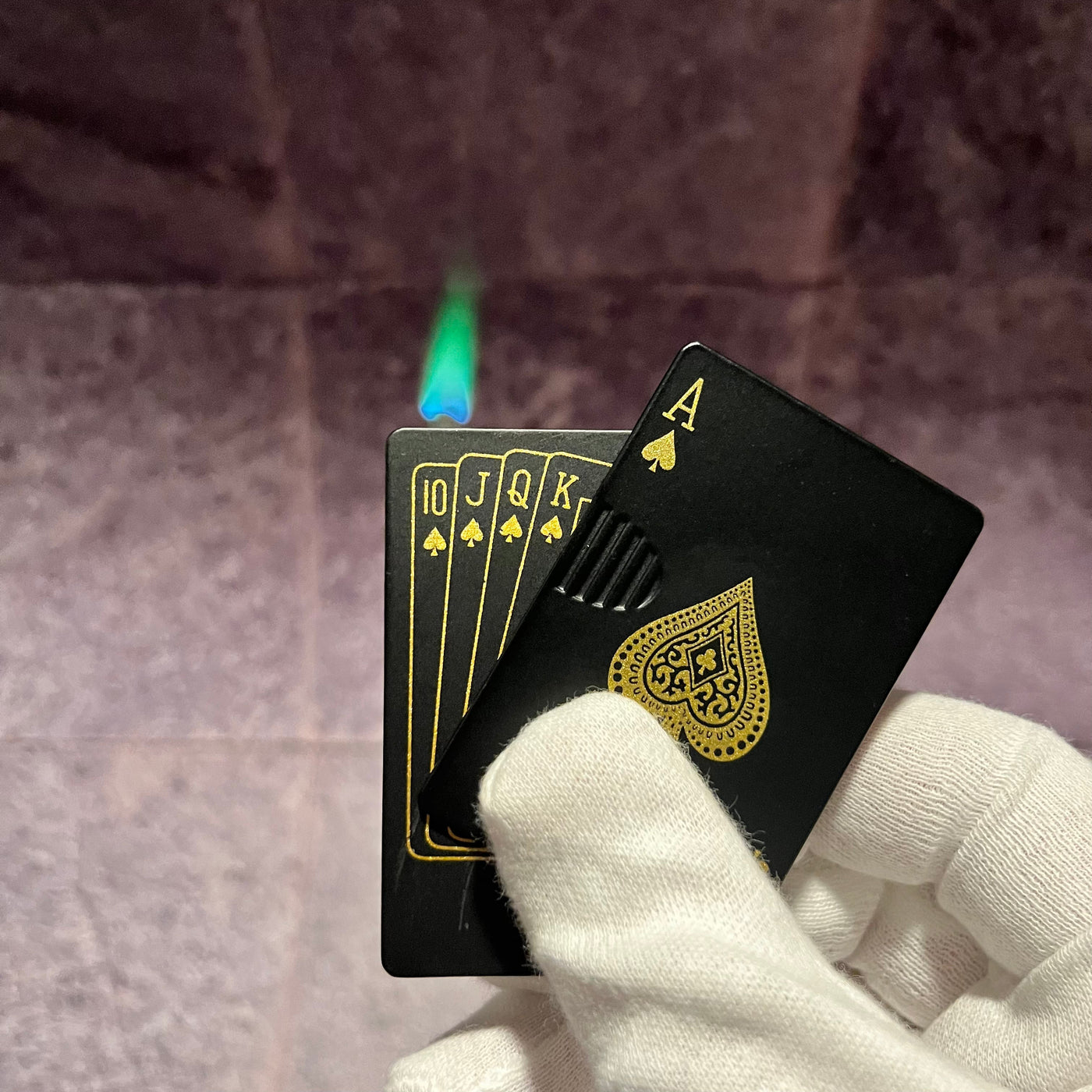 Black Ace Poker Card Torch Lighter – refillable butane lighter shaped like an Ace of Spades card, producing a green-blue torch flame while held in a gloved hand
