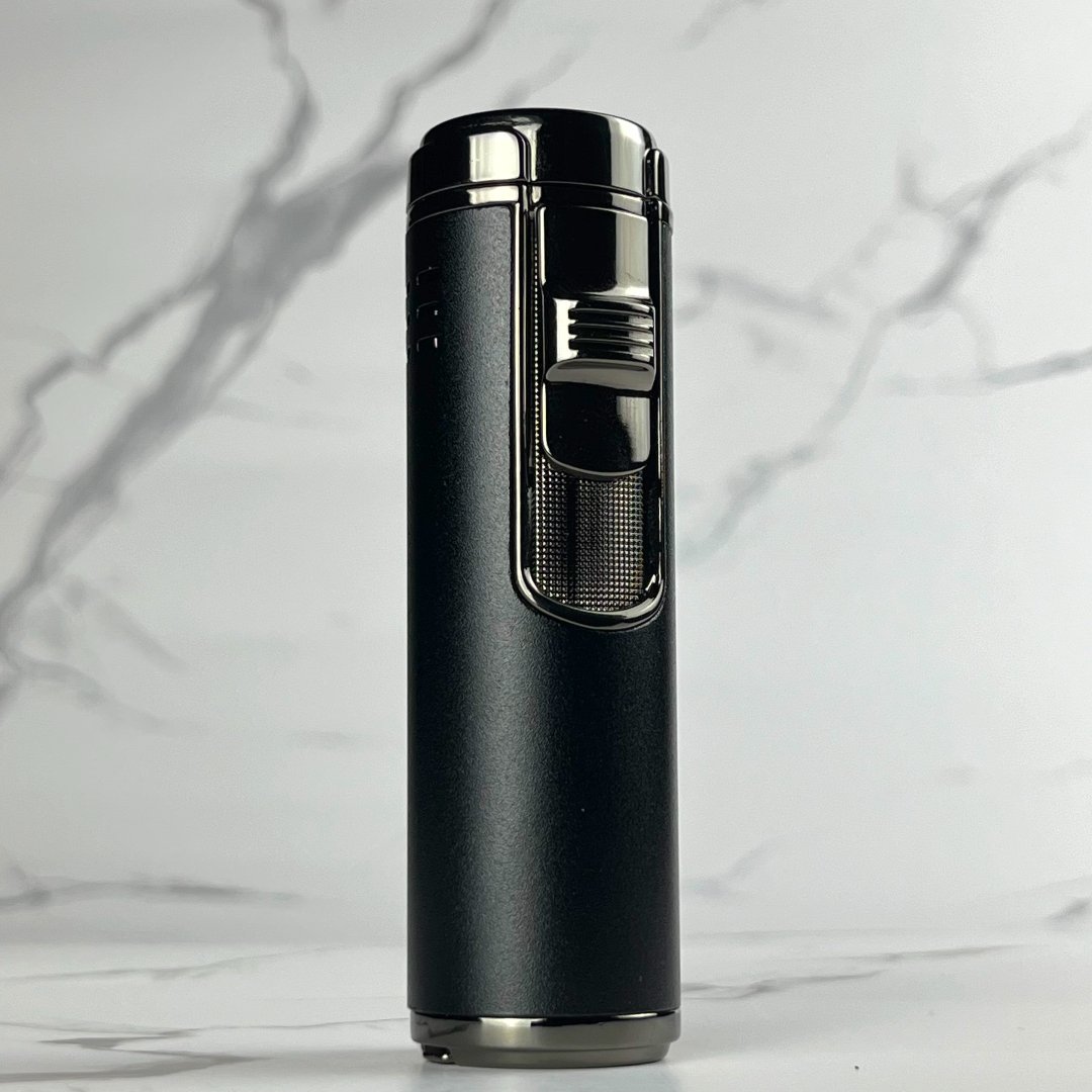 Matte black refillable torch lighter with chrome black ignition switch and textured grip, standing on marble background.