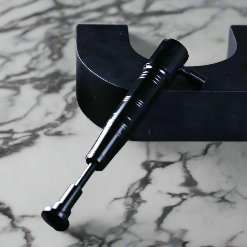 Black premium torch lighter laid horizontally on a stylish black stand with a marble tabletop.