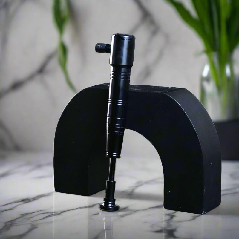 Sleek black torch lighter standing upright on a contemporary black display with a marble background.