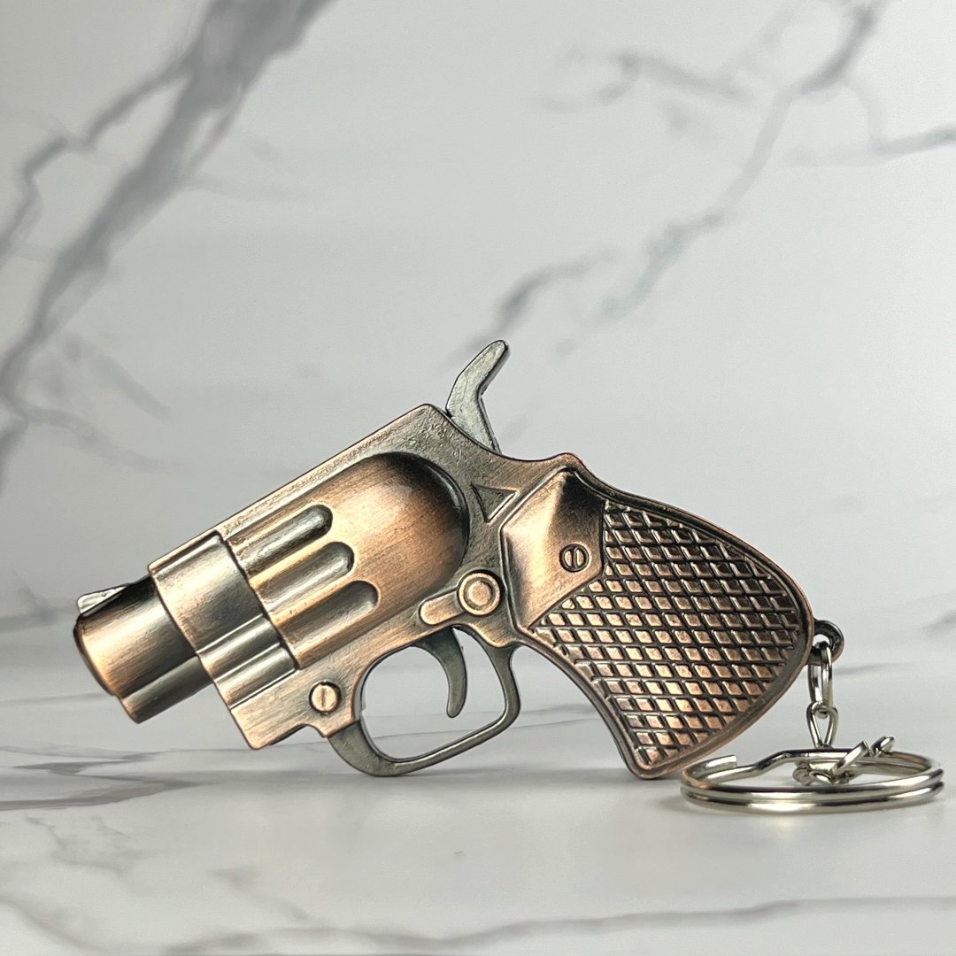 Mini revolver refillable lighter with antique bronze finish and diamond-patterned grip, displayed flat with keychain attached.