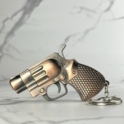 Mini revolver refillable lighter with antique bronze finish and diamond-patterned grip, displayed flat with keychain attached.