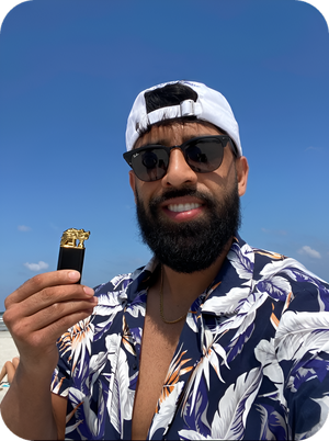 Man holding a gold animal torch lighter at the beach, wearing sunglasses and tropical shirt