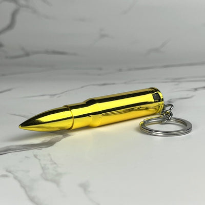 Gold-colored bullet-shaped refillable lighter with keychain ring, displayed on a marble surface.