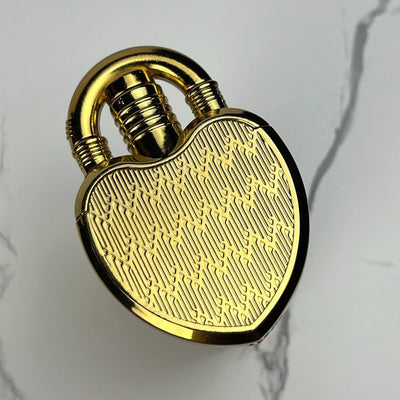 Shiny gold heart-shaped lock lighter with an intricate etched design.