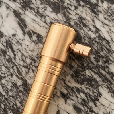 Golden torch lighter showcasing its ergonomic design and refined finish against a marbled background.