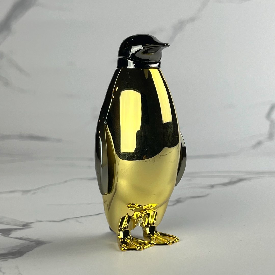 Luxurious gold penguin lighter with chrome accents and a high-shine finish, captured against a clean marble surface.