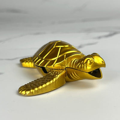 Close-up of a gold turtle-shaped lighter resting on a white marble surface.