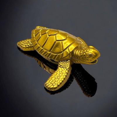 Gold turtle lighter with shell details, shown on a glossy black reflective surface.