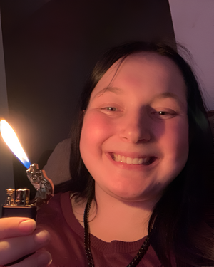Smiling customer holding an dragon-themed refillable lighter with a soft flame in a dim setting