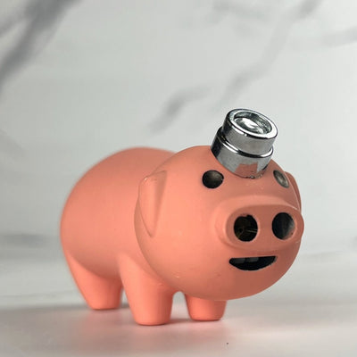 Cute pig-shaped refillable torch lighter with a metal ignition cap, displayed on a marble background.