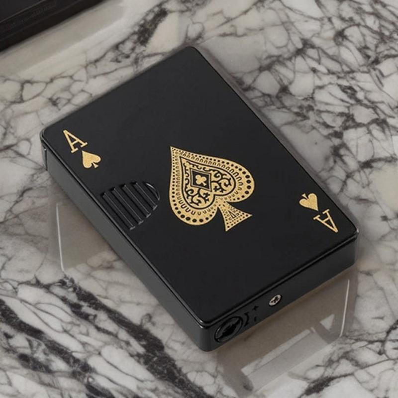 Black and gold playing card-themed lighter with an intricate ace of spades design, set on a marble surface.