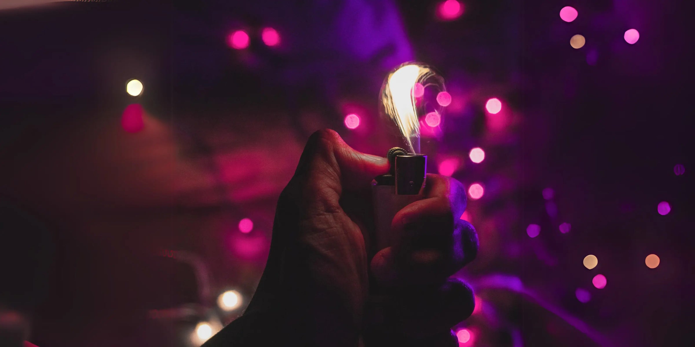 Refillable lighter lit with a bright flame, hand-held against a vivid purple background – desktop view by LighterLoungeCo