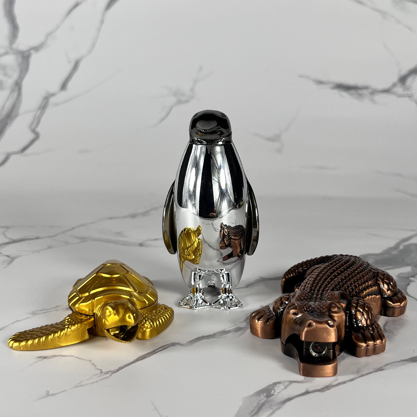 Sea Flame Bundle – complete 3-piece refillable butane lighter set featuring a gold Sea Turtle, silver Penguin Flame, and bronze Crocodile Torch, displayed on a marble backdrop.
