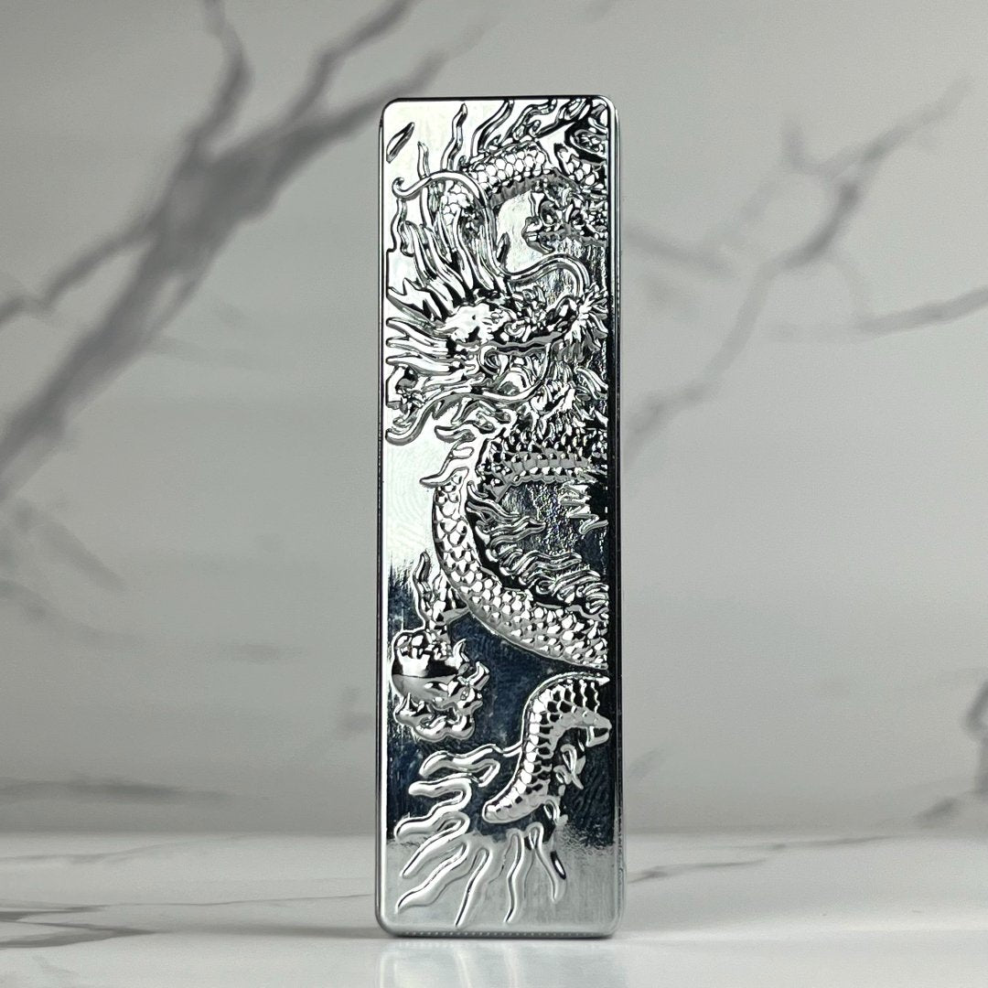 Sleek silver bar lighter featuring an intricate engraved dragon design on a reflective chrome finish.