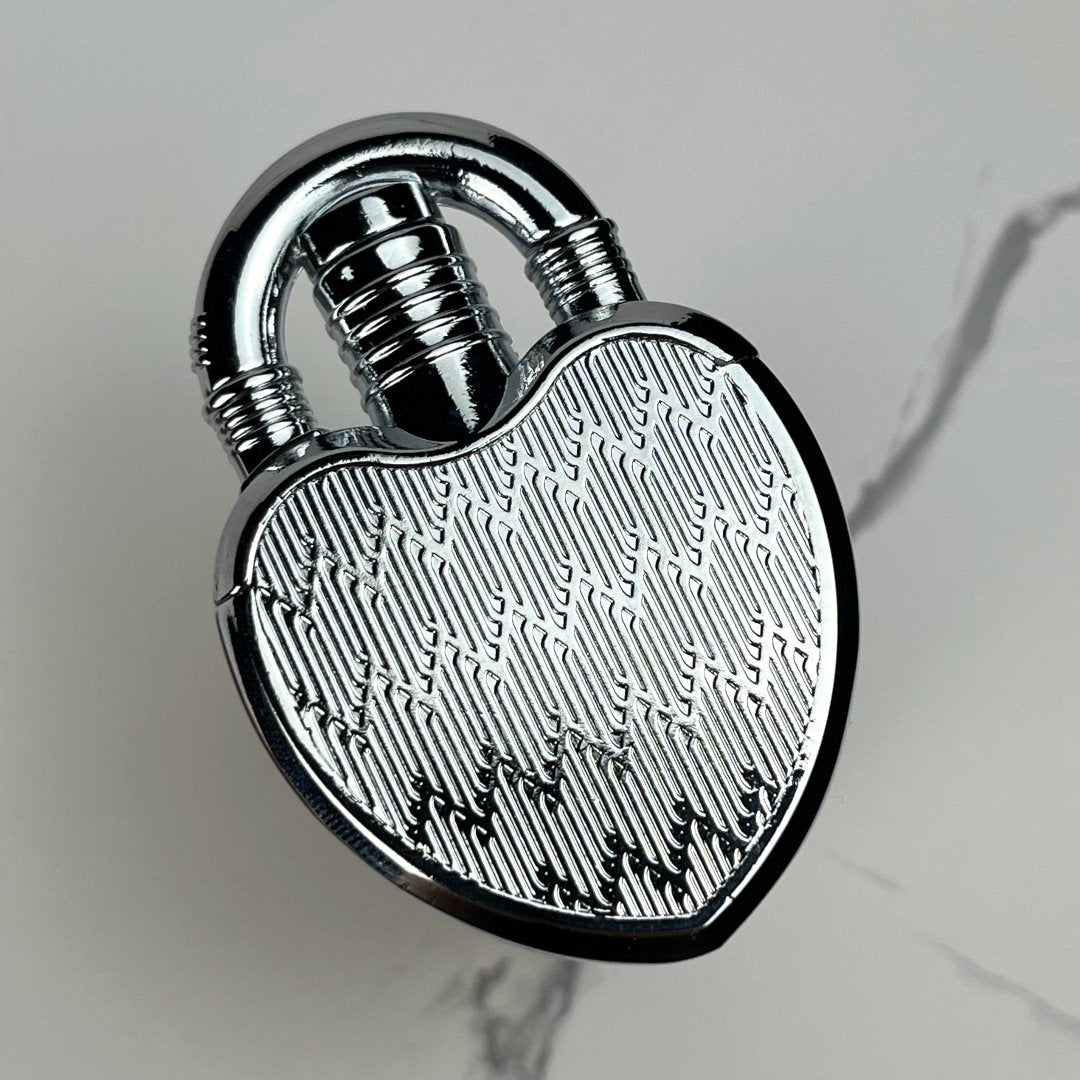 Polished silver heart-shaped lock lighter featuring a detailed etched surface.


